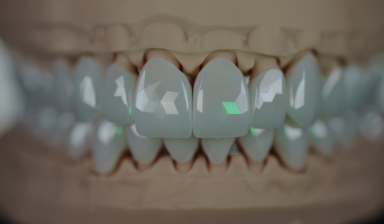Macro shot of a faceted tooth — the cut lines and the light breaking across them must both read. Dark ground, single light.
